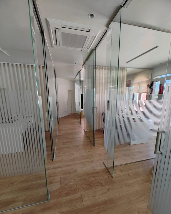 Corredor interior do escritório, com divisórias de vidro e pavimento em madeira