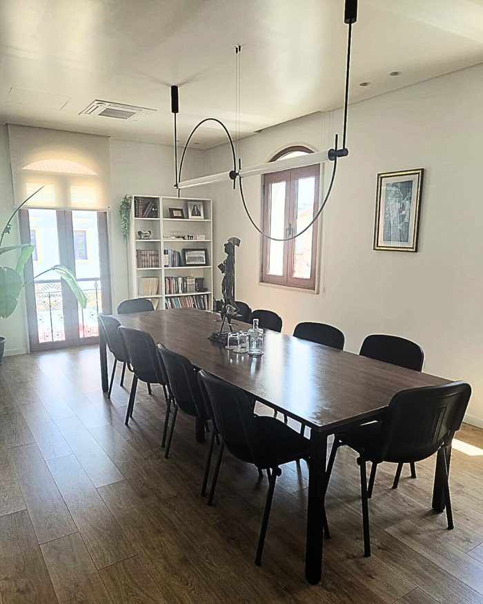 Sala de reuniões do escritório, com mesa comprida, estante de livros e luz natural